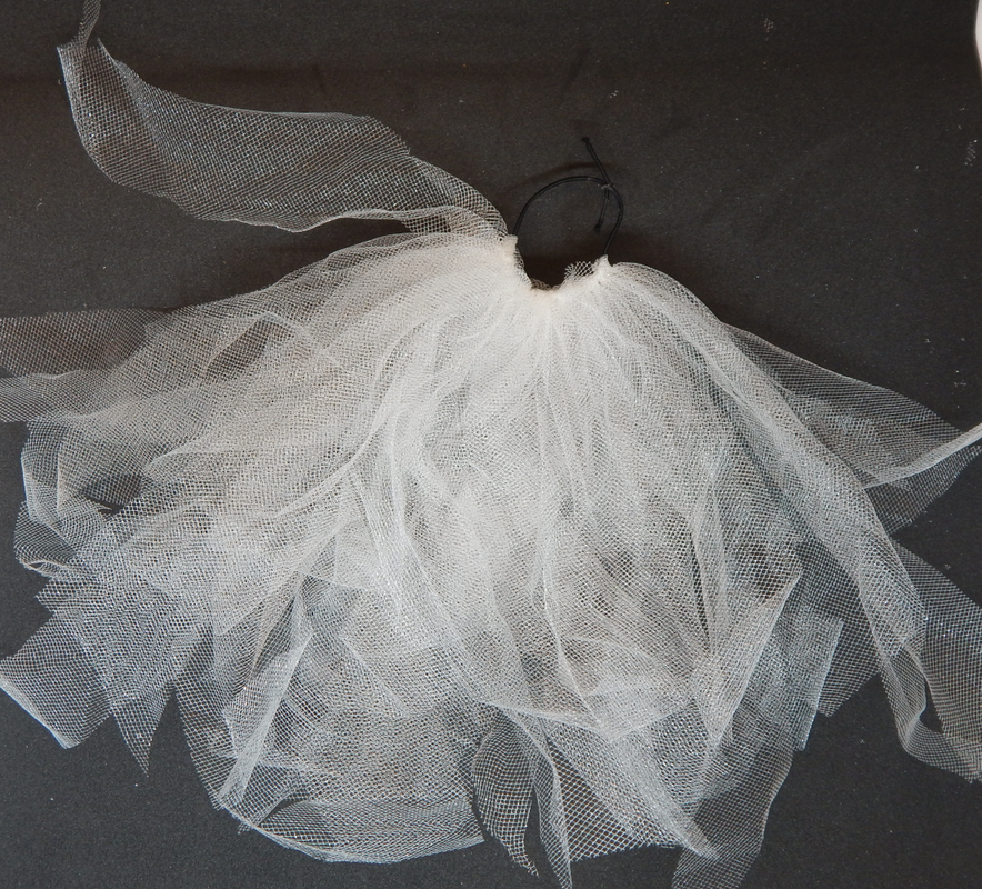 Multiple pieces of white tulle attached to a black elastic band. About 1/3 the band is covered.