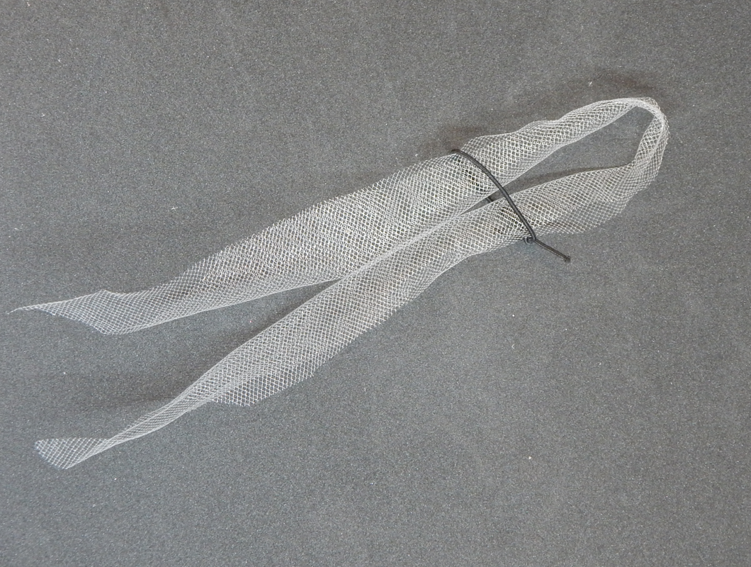A piece of white tulle is folded in half with a black elastic band encircling it a few inches down.