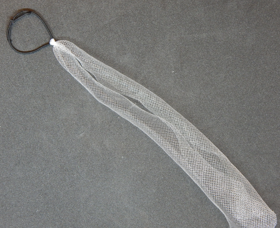 A piece of white tulle attached to a black elastic band rests diagonally on a black background