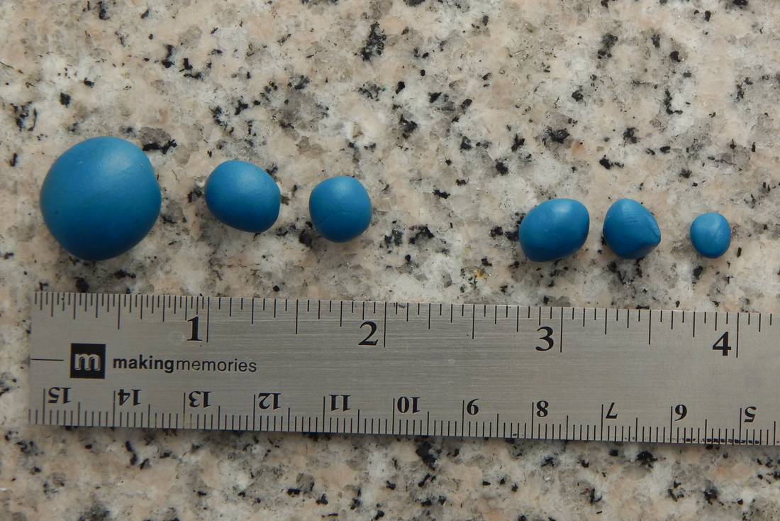 Six pieces of blue clay in graduated sizes above a silver ruler