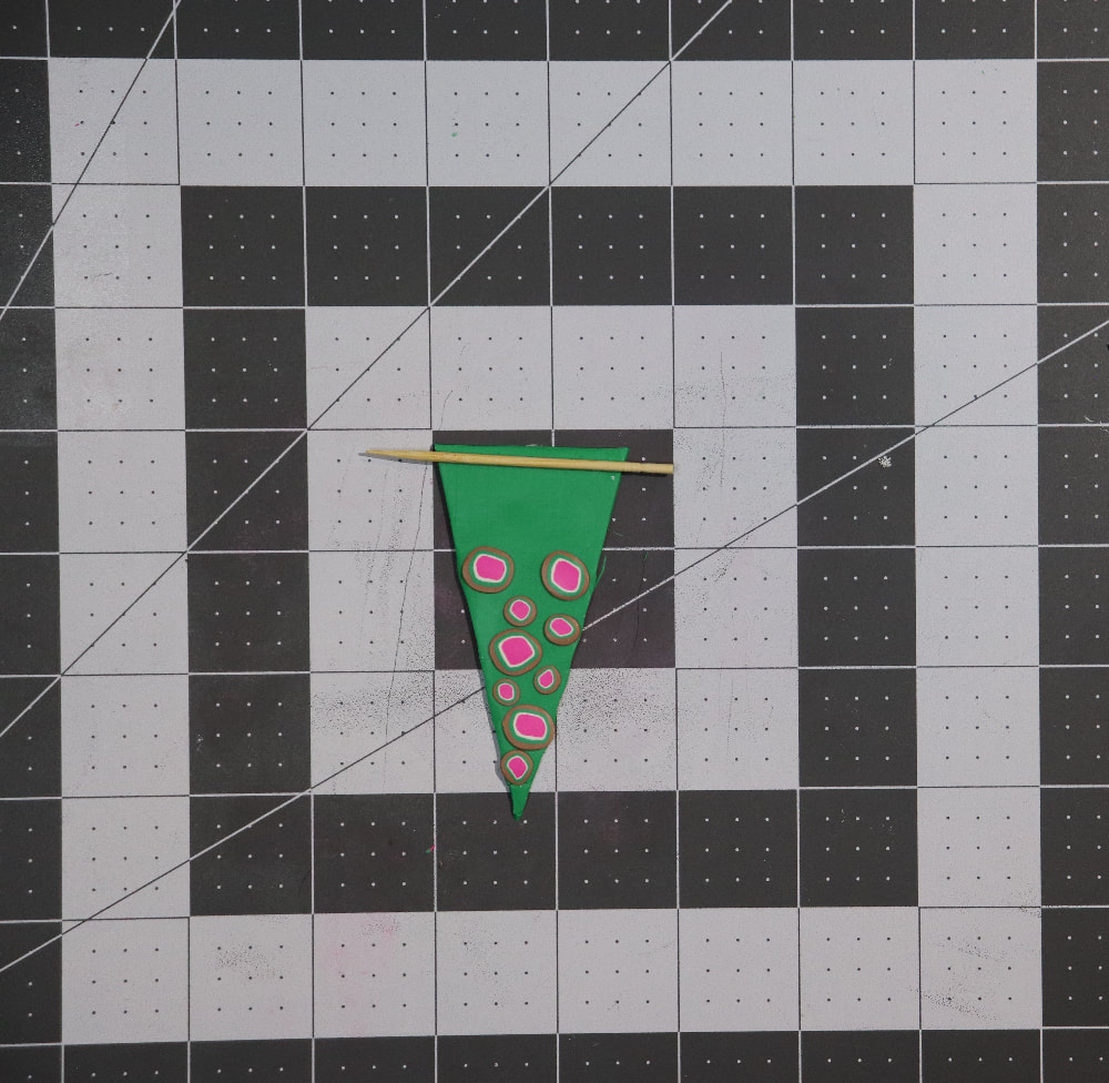The decorated green triangle on a cutting mat with a toothpick at the top (the shortest side of the triangle)